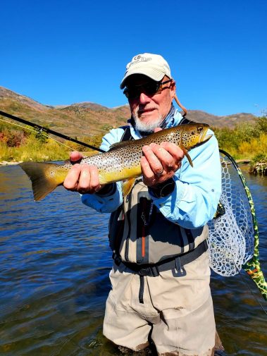 A fly fisherman fighting a trout on a Utah river during the Winter