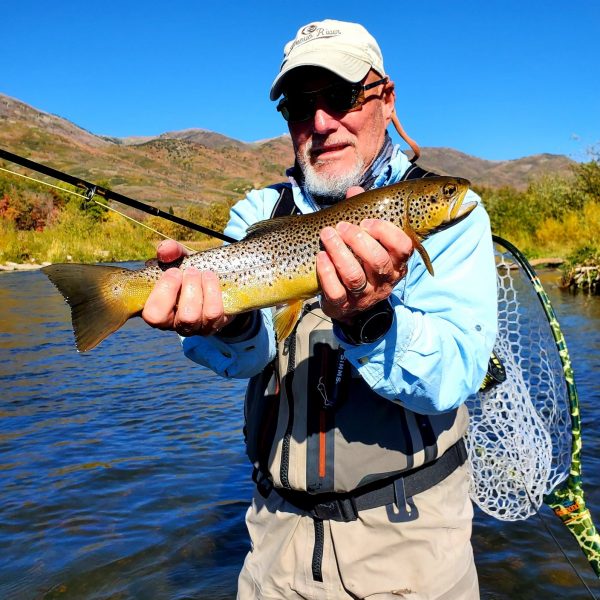 A fly fisherman fighting a trout on a Utah river during the Winter