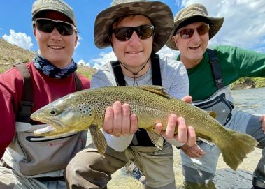 A father and two sons with a big brown trout caught on a Jeremy Allan Fly Fishing trip