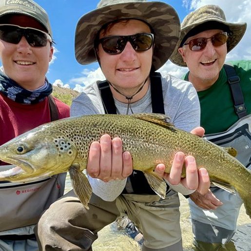 A father and two sons with a big brown trout caught on a Jeremy Allan Fly Fishing trip
