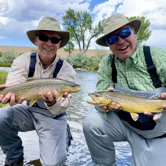 Two Jeremy Allan Fly Fishing clients holding big brown trout.