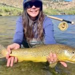 A lady holding a giant brown trout caught on a small stream in Utah.