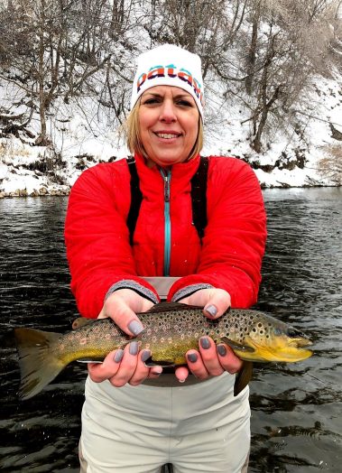 Woman fly fisherman holding a brown trout
