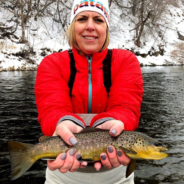 Woman fly fisherman holding a brown trout
