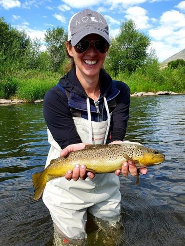 A lady fly fisher with a big brown trout on the Provo River, Utah