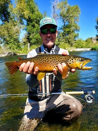 A fly fisherman with a big brown trout on the Weber River