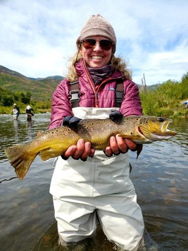 A lady fly fisher with a brown trout on the Provo River, Utah