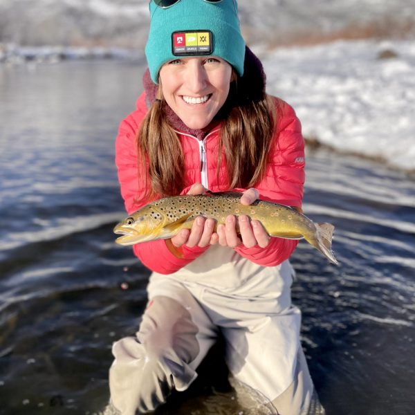 A woman with a brown trout caught while fly fishing in the Winter
