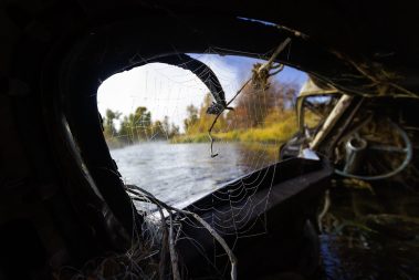 A spider web in the window of an old car looking into the Weber River. Fine art prints by Jeremy Allan