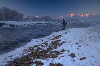 A fly fisherman standing in the Provo River during the Winter