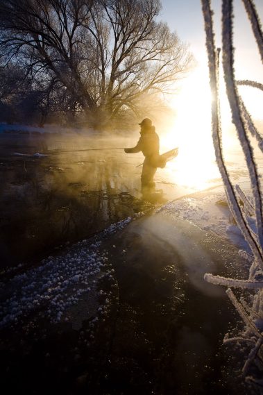 A fly fisherman standing in the Provo River during the Winter