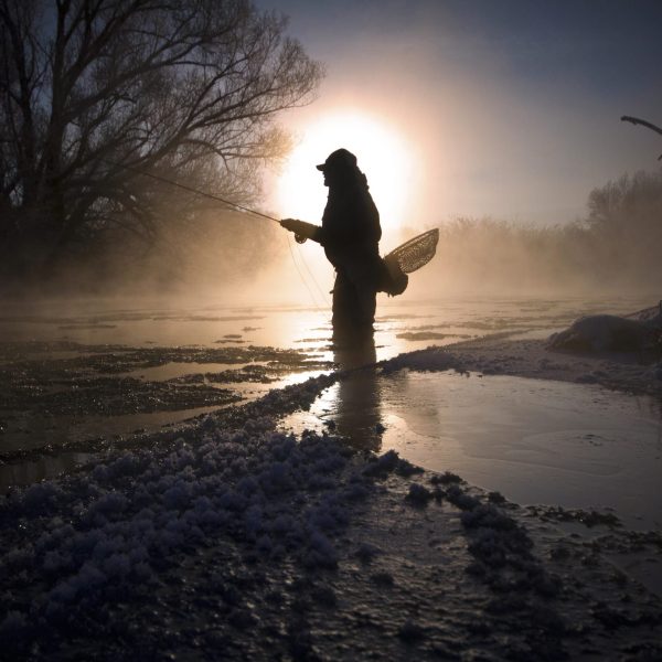 A fly fisherman standing in the Provo River during the Winter