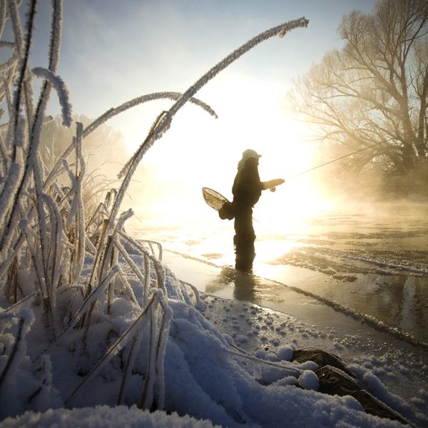 A fly fisherman standing in the Provo River during the Winter