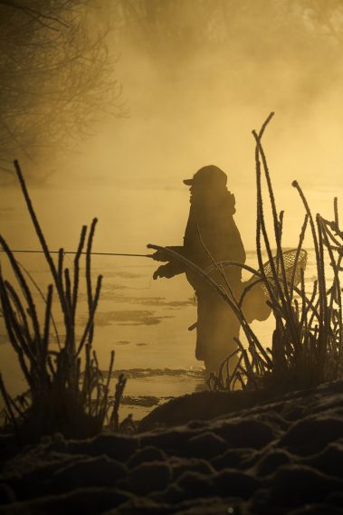 A fly fisherman standing in the Provo River during the Winter