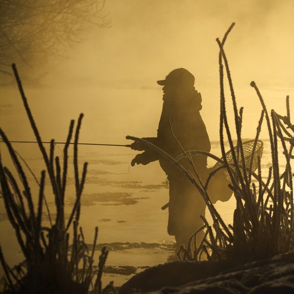 A fly fisherman standing in the Provo River during the Winter