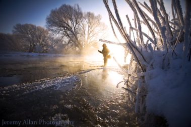 A fly fisherman standing in the Provo River during the Winter