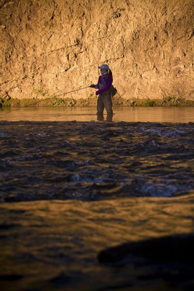 A woman fly fisher casting on the Provo River
