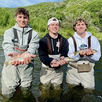 Three brothers each with a trout caught while fly fishing on the Provo River