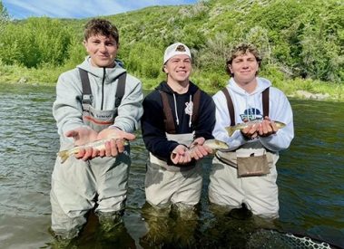 Three brothers each with a trout caught while fly fishing on the Provo River