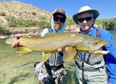 A fly fishing guide and client with a big brown trout caught on a guided fly fishing trip in Utah with Jeremy Allan