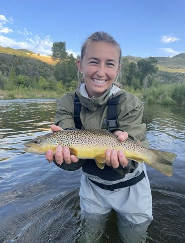 A happy girl holding a trout caught on the Provo River while fly fishing with Jeremy Allan Fly Fishing